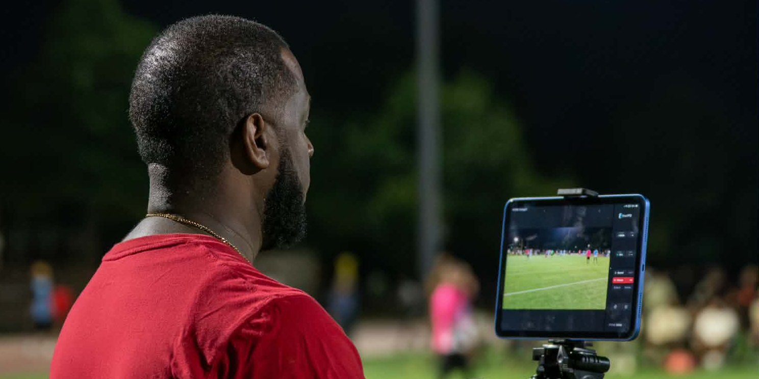 A camera operator running smartPTZ on an iPad at a night soccer match
